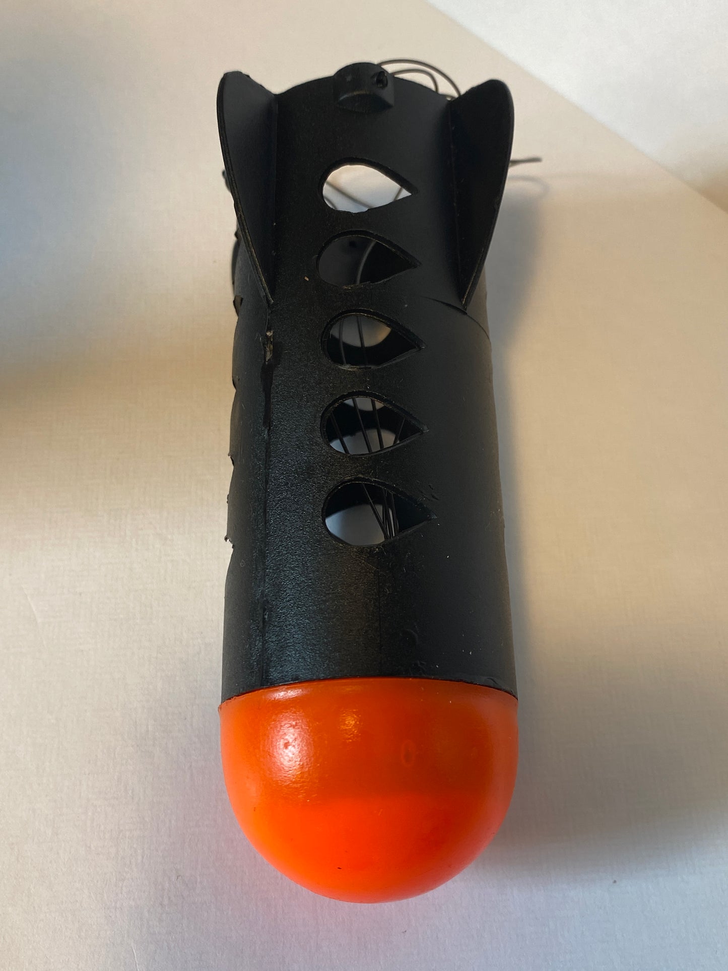 Black and orange spod rocket with cut-out design on a light gray background