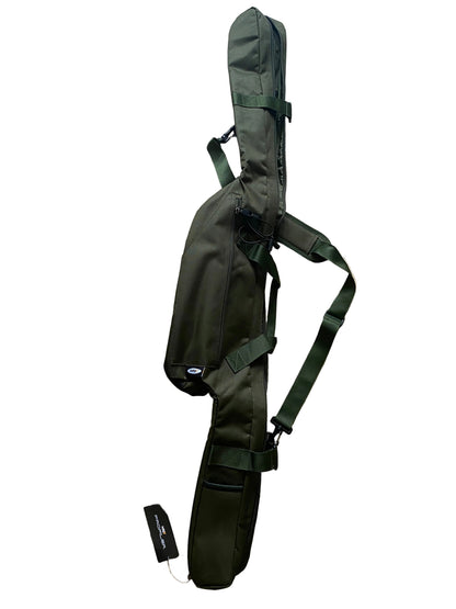 An olive green rifle case with a shoulder strap, laid flat on a beige tiled floor. A small black hangtag is visible next to the case.