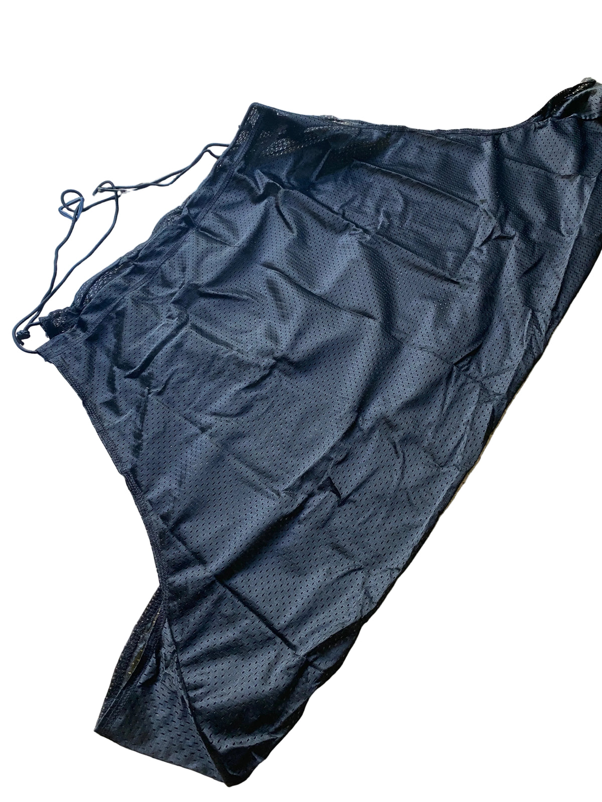 A black textured drawstring bag or pouch made of a mesh-like fabric, laid flat on a beige tiled floor.