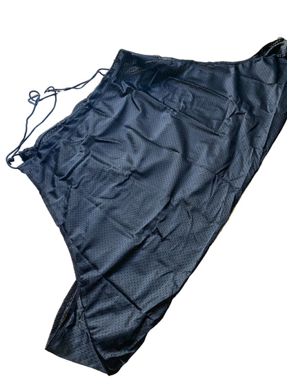 A black textured drawstring bag or pouch made of a mesh-like fabric, laid flat on a beige tiled floor.