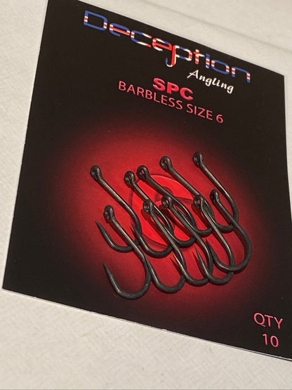 A package of Deception Angling SPC Barbless Size 6 hooks, featuring a black card with a red glow and an illustration of six dark hooks, placed on a white textured surface.