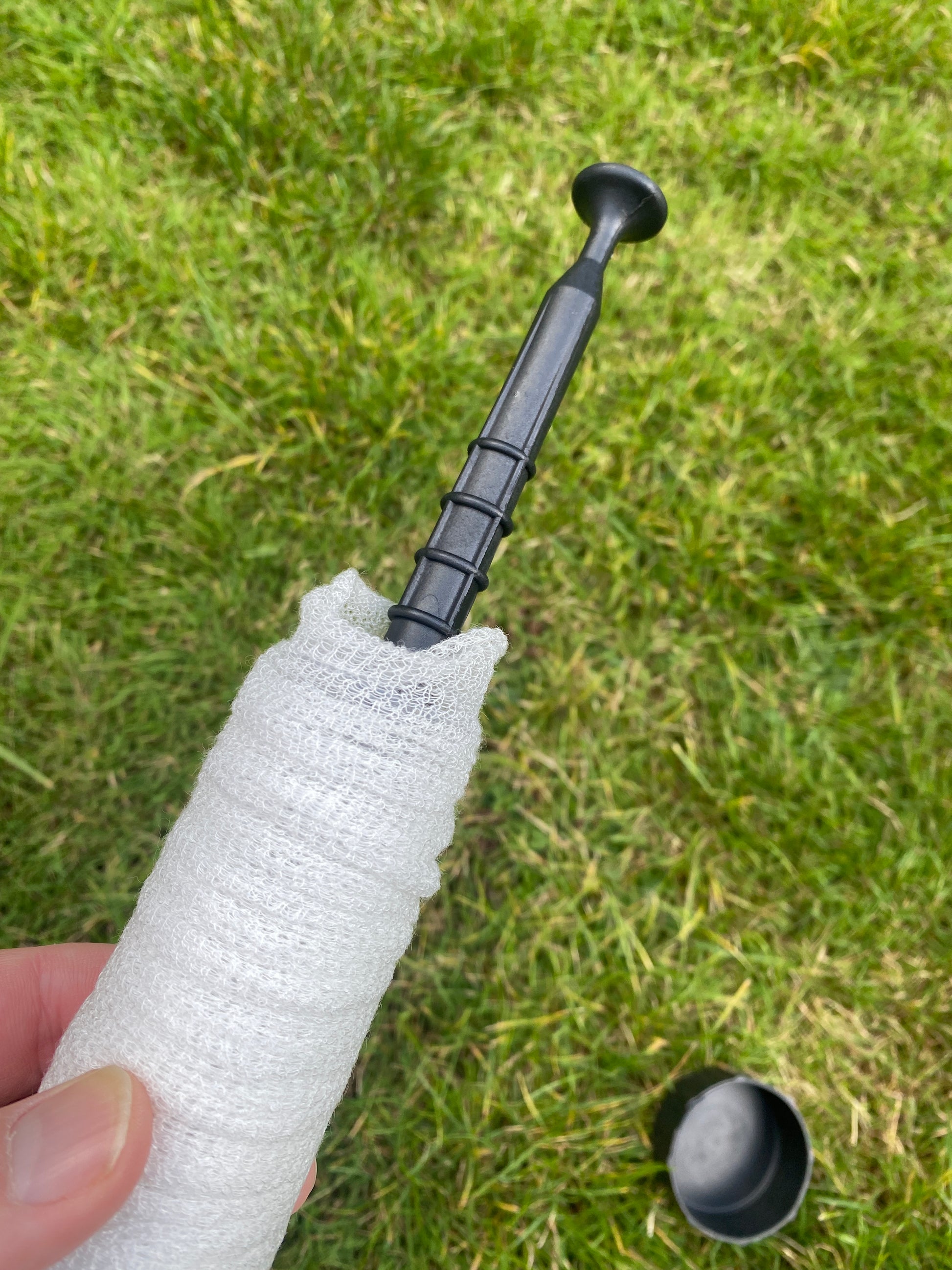 Spool of PVA mesh with black plastic plunger with a grass background