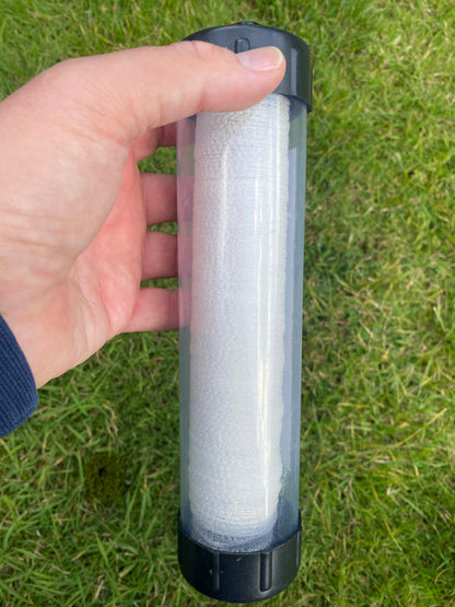 Hand holding a tube of PVA mesh against a grass background
